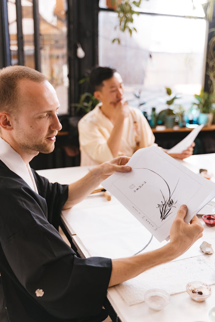 Two men practicing traditional Japanese calligraphy art indoors, focusing on a zen technique.